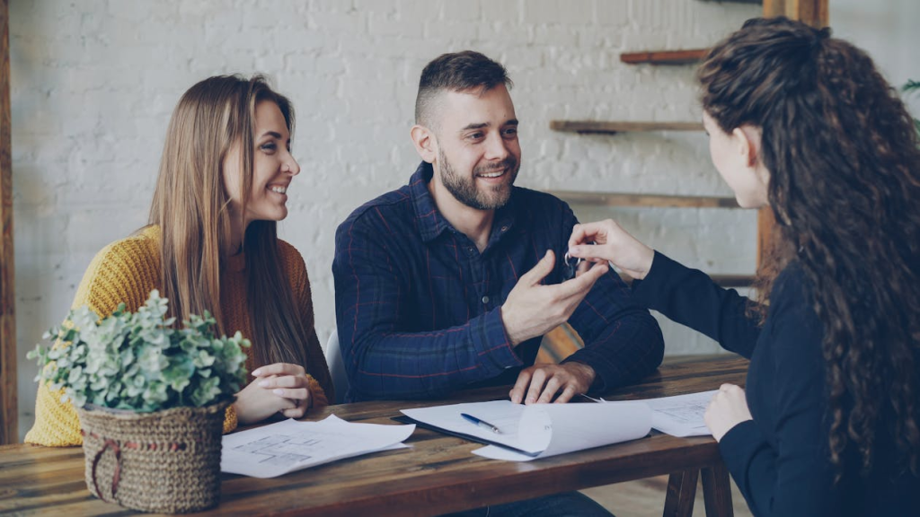 First-time home buyers receiving house keys from their real estate agent at closing