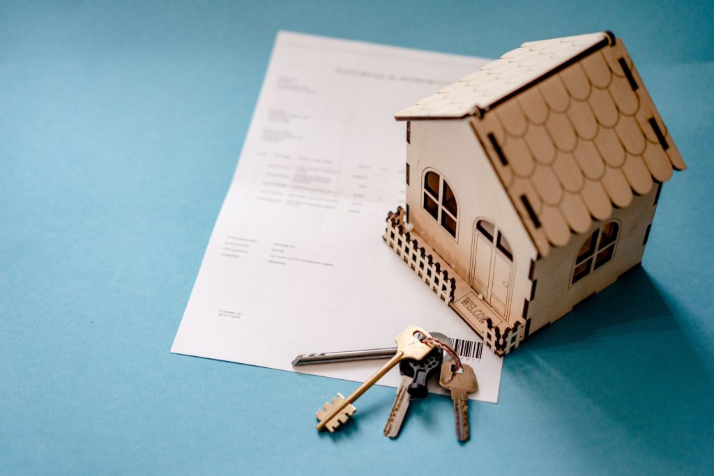 House keys and a real estate contract with a wooden house model